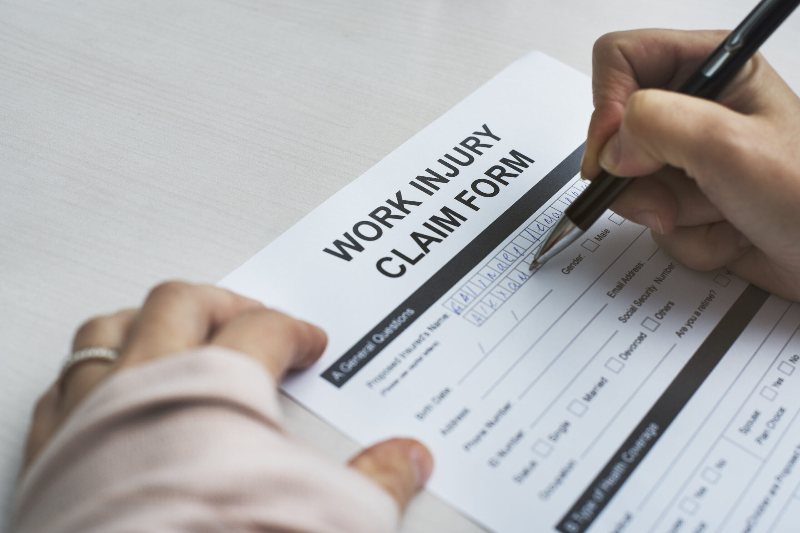 Hand holding pen and filling our workers compensation claim